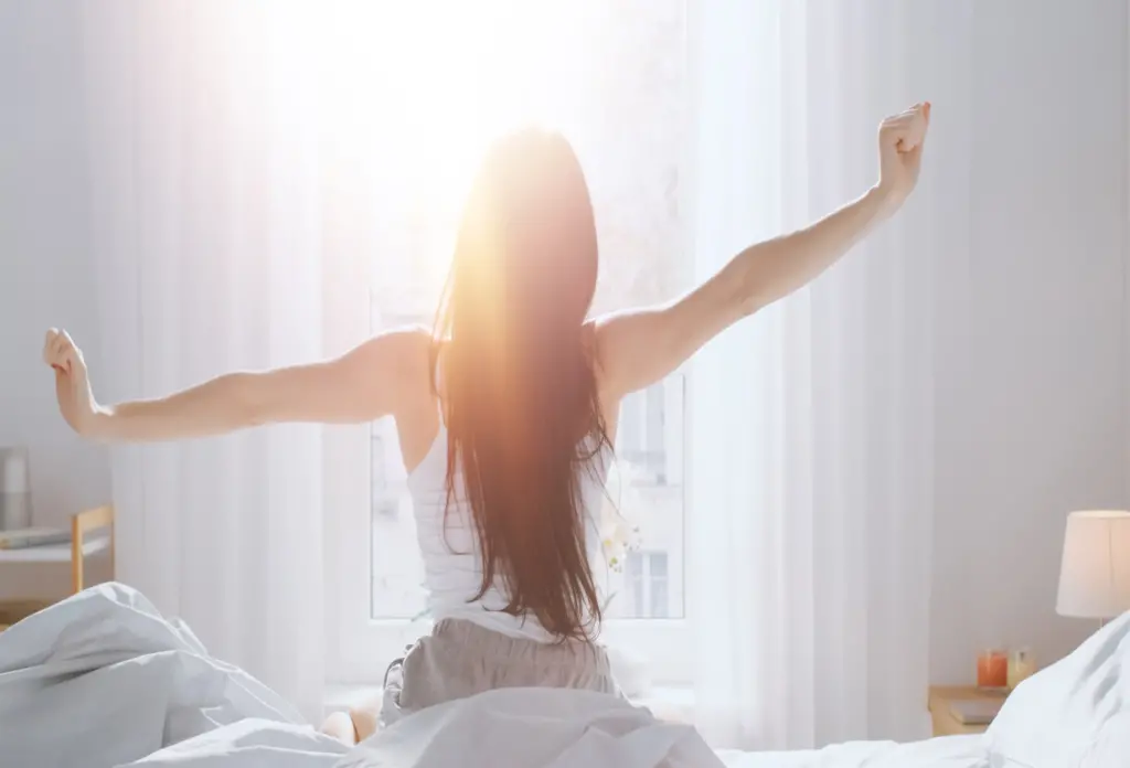 Woman waking up and stretching in the sunshine - waking up to gratitude